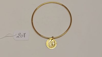 Gros plan sur un bracelet en or orné d'une pièce de monnaie