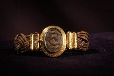 a close up of a gold bracelet with a roman coin on it