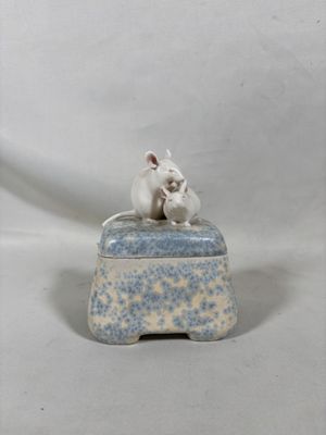 figurine en porcelaine représentant deux souris assises sur une boîte bleue et blanche