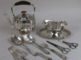 a silver tea set with silverware on a white table