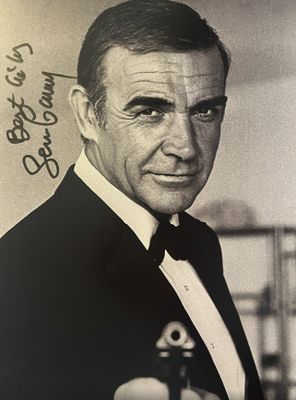 photographie en noir et blanc d'un homme en smoking tenant un pistolet