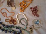 many different necklaces and bracelets laid out on a table