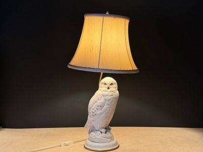 une lampe en forme de chouette blanche posée sur une table, avec un abat-jour