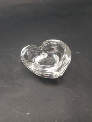 un cendrier en verre en forme de cœur posé sur une table noire