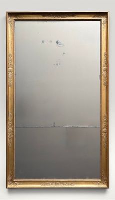 a gold framed mirror hanging on a wall next to a white wall