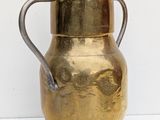 an old brass pitcher with a handle on a white surface