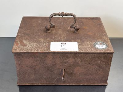 une boîte en métal munie d'une poignée, posée sur une table