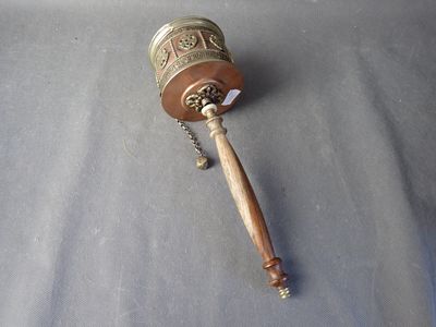 une petite clochette en métal avec un manche en bois posée sur une table