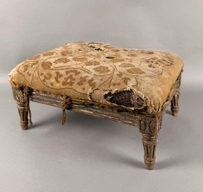 un vieux tabouret en bois avec une assise rembourrée de couleur beige clair