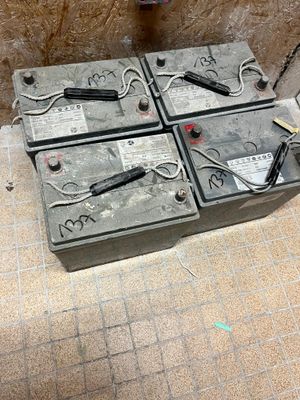 plusieurs batteries posées sur un sol carrelé, à côté d'une borne d'incendie