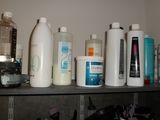 many bottles and containers on a shelf in the bathroom