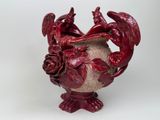 a red vase with two birds on it on a white background