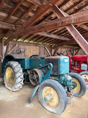deux vieux tracteurs dans une grange au toit en bois