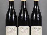 trois bouteilles de vin sont alignées sur une table