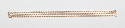 un gros plan d'un bracelet en or muni d'une chaîne, posé sur une surface blanche