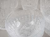 several clear glass bowls and cups are lined up on a white surface