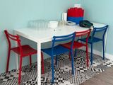 une table blanche avec des chaises rouges et bleues dans une pièce bleue