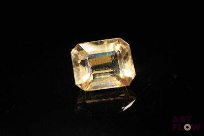 a close up of a yellow sapphire stone on a black surface