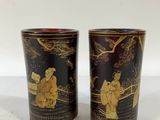 two black and gold vases sitting on top of a white table