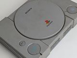 a sony game console sitting on a table next to a cell phone