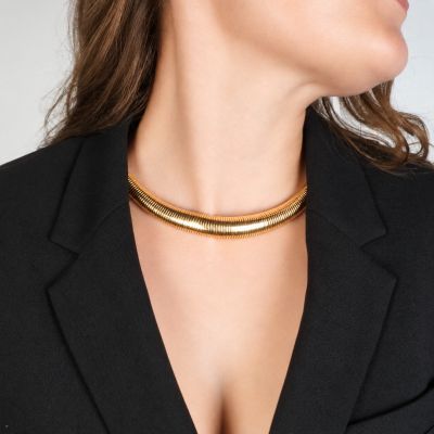 une femme portant un blazer noir et un collier ras-du-cou doré