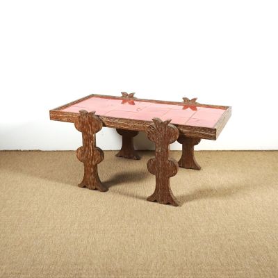 une table en bois posée à même le sol, dont le plateau est recouvert de carreaux roses