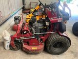 un homme debout à côté d'une tondeuse à gazon rouge dans un garage