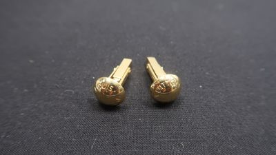 a pair of gold plated earrings sitting on top of a black cloth