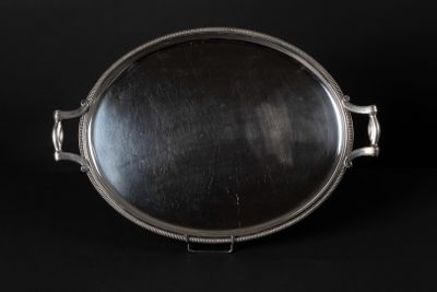 an antique silver plate on a black background with a reflection in it