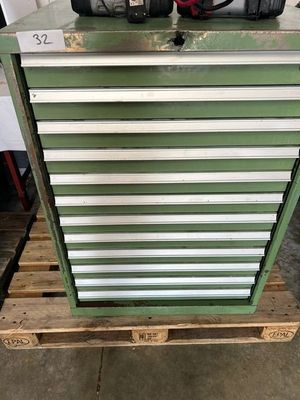 une armoire à outils verte posée sur une palette dans un garage