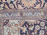 close up of a persian rug with a blue background and a brown border