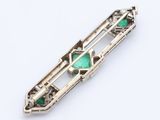 a close up of a silver broochle with green stones on it