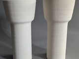 two white vases sitting next to each other on a table