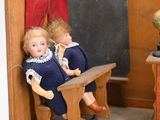 two dolls sitting on a bench in the corner of a room