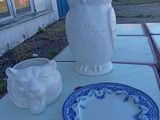 une statue de chouette blanche posée sur une table, à côté d'une assiette bleue et blanche