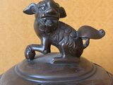 a bronze statue of a dog on top of a bowl