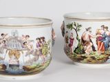une paire de tasses en porcelaine ornées de personnages peints, posées sur une table
