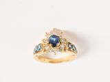 gros plan d'une bague en or avec un saphir et des diamants