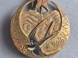 a small gold medal with a bird and a star on it