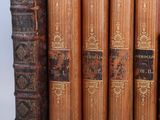 several old books are stacked on top of each other on a shelf