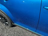 a small blue car parked on the side of the road