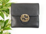 a black leather wallet with a gold ring on the front