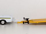 a toy truck pulling a trailer behind it on a white surface
