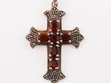 une croix en argent ornée de pierres rouges sur fond blanc