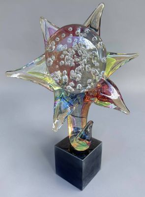 un gros plan d'une sculpture en verre représentant une fleur sur un socle noir