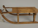 une vieille luge en bois posée sur une surface blanche