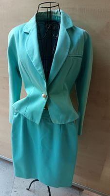 a suit on a mannequin stand in front of a wall