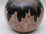 a black and pink vase sitting on a white surface