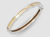 un gros plan d'un bracelet rigide en argent et or sur fond blanc