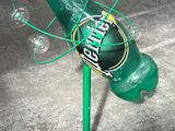a green bottle with bubbles attached to it on a stand